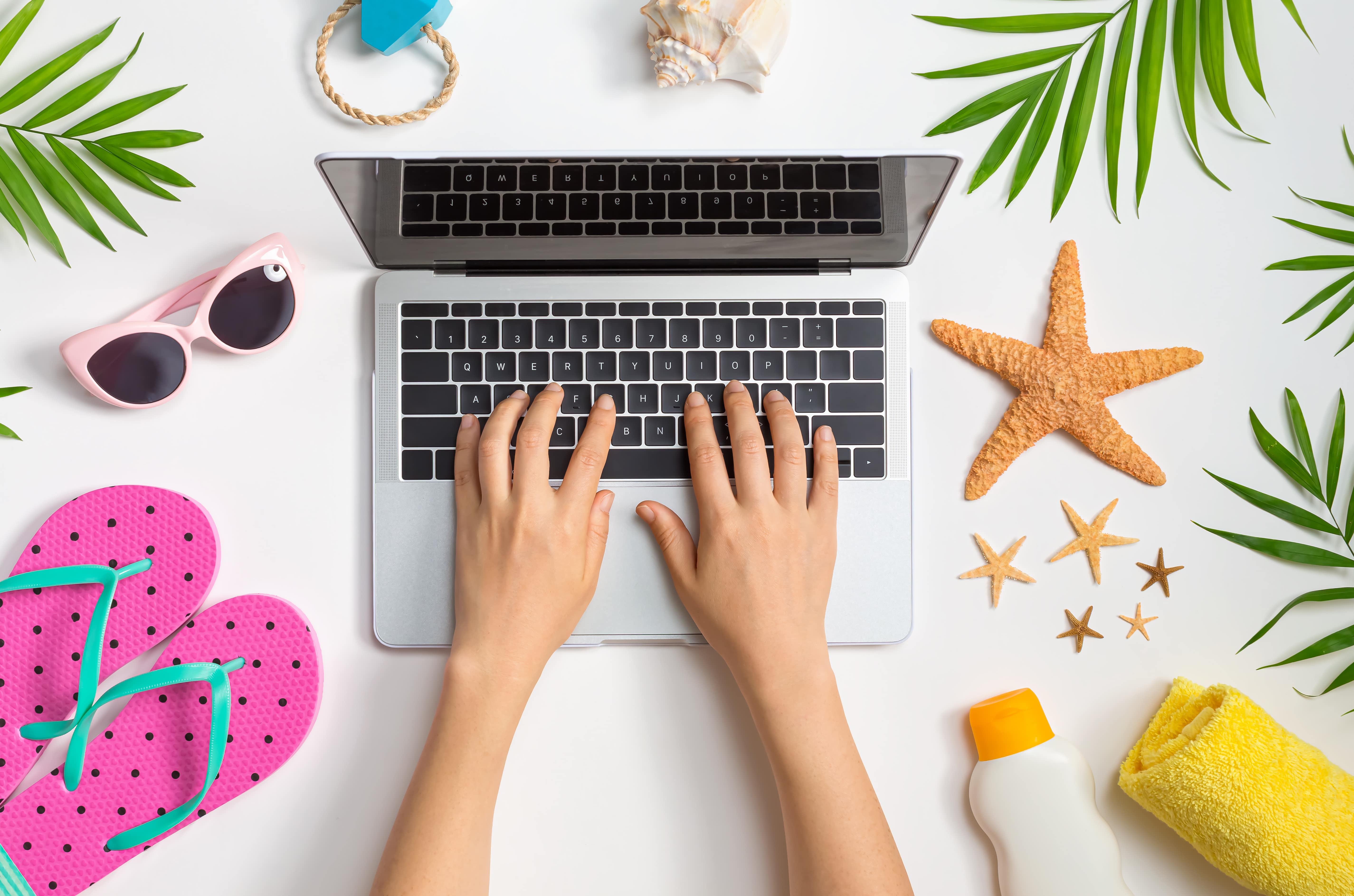 hands on laptop surrounded by summer themed objects looking up ways to motivate your team